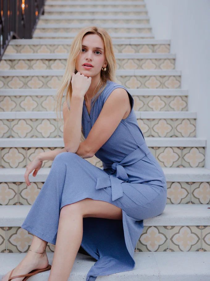 Woman wearing a blue Charlotte belted maxi dress with a V-neckline, tie waist belt, and side leg slit from The Pink Doxie Boutique.
