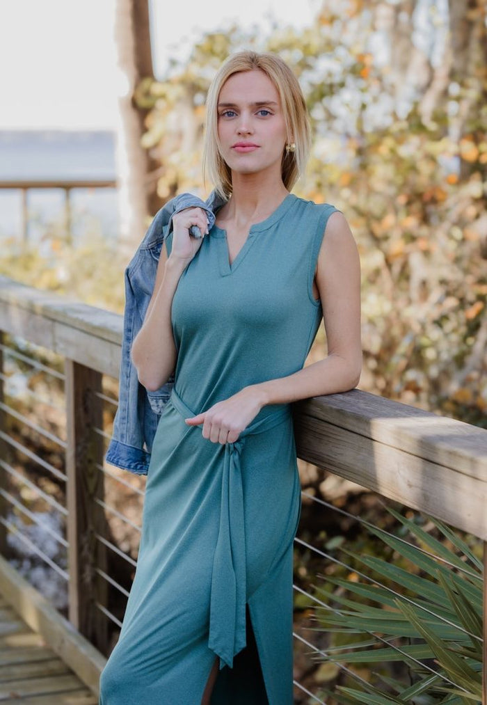 Woman wearing a green Charlotte belted maxi dress with a V-neckline, tie waist belt, and side leg slit from The Pink Doxie Boutique.