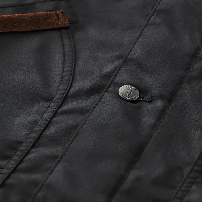 Close-up of a dark charcoal gray jacket or coat fabric with a brown leather trim detail and a silver metal snap button.