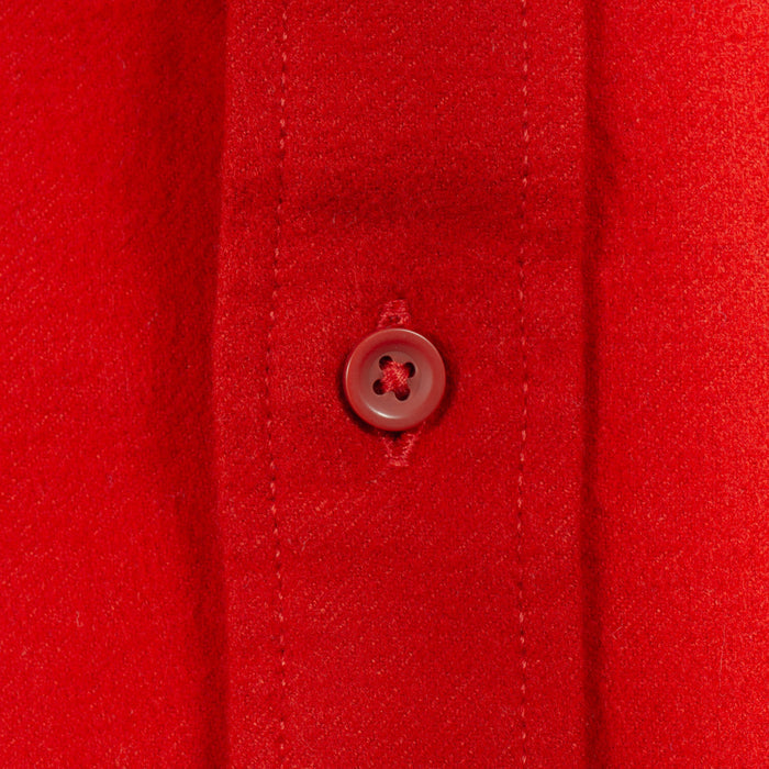 Close-up of a bright red button-down shirt fabric with a matching red button on the placket.