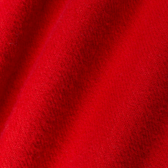 A close-up of bright red textured fabric with soft diagonal folds and a plush, nubby surface.