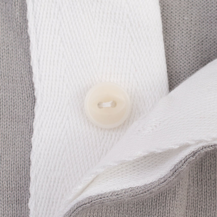 Close-up of a gray knit garment with a white collar and a round off-white button.