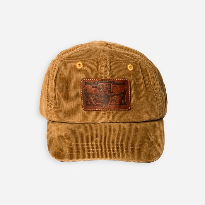 A brown corduroy baseball cap with a brown leather patch on the front featuring a stylized eagle logo, photographed against a light gray background.