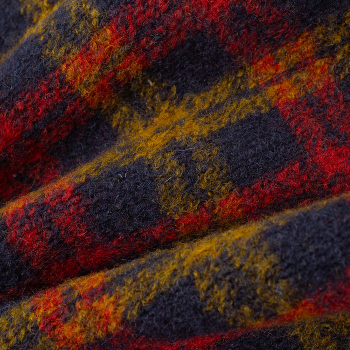 A close-up of a textured, fuzzy plaid fabric with a pattern of dark navy, red, and mustard yellow.