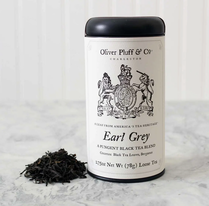 A canister of Oliver Pluff & Co Earl Grey loose black tea leaves with bergamot, alongside a pile of black tea leaves.